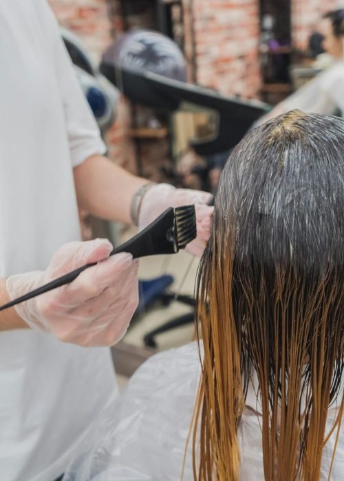 Hair coloring process in a salon, showcasing stylist applying color to client's hair.