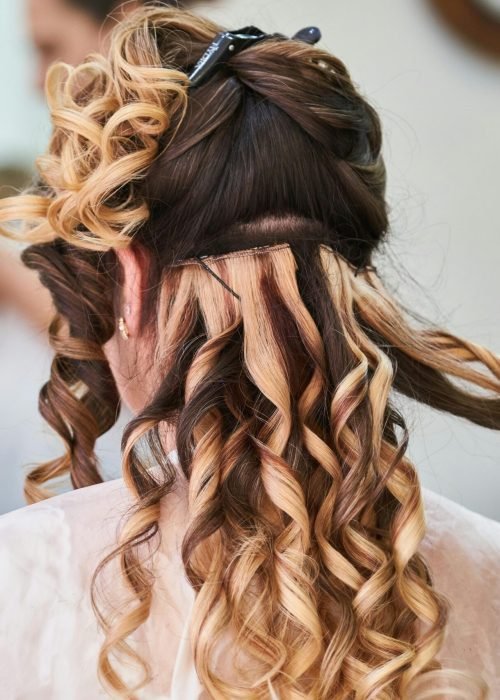 Close-up of hairstylist perfecting curls on a woman's hair in a salon setting.