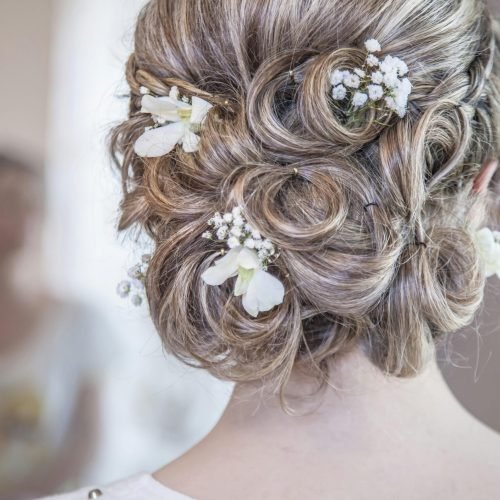 Close-up of an elegant bridal hairstyle featuring delicate white flowers, perfect for a wedding day.