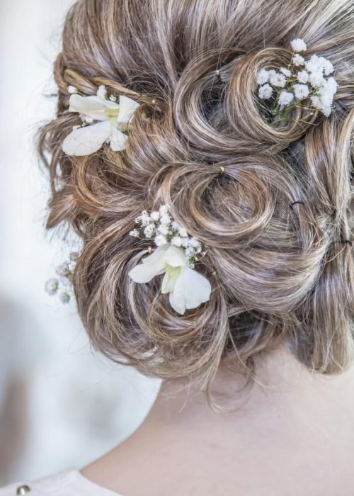 Close-up of an elegant bridal hairstyle featuring delicate white flowers, perfect for a wedding day.
