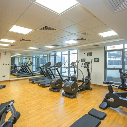 Spacious indoor gym with treadmills, stationary bikes, and exercise equipment on a wooden floor.
